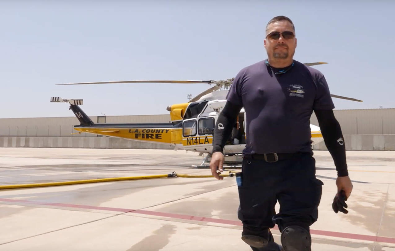 Joe Martinez poses in front of an LA County Fire Department helicopter.